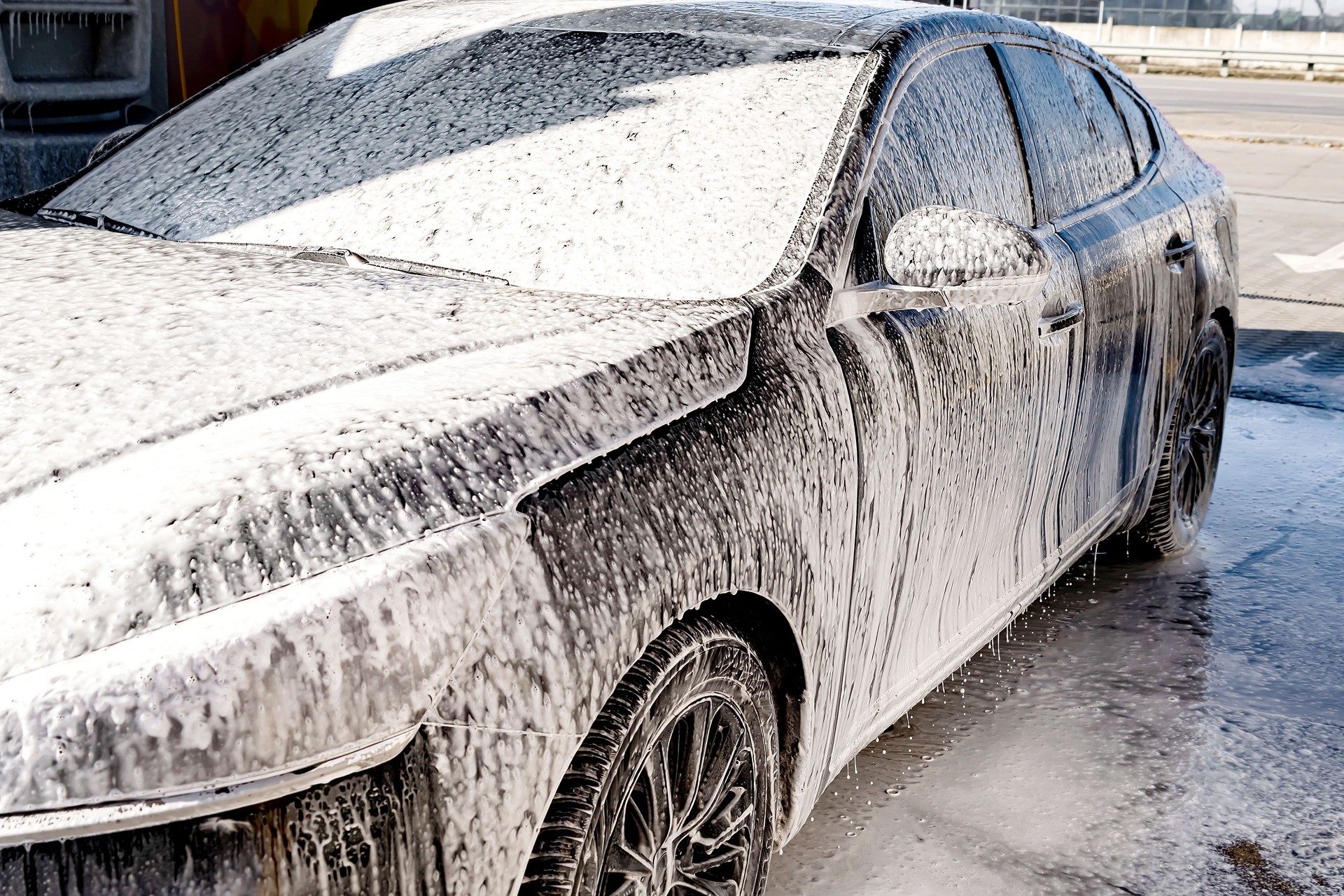 Washing car with contactless high pressure water jet,equipment pump in self service car wash.Vehicle covered with foam chemical detergents